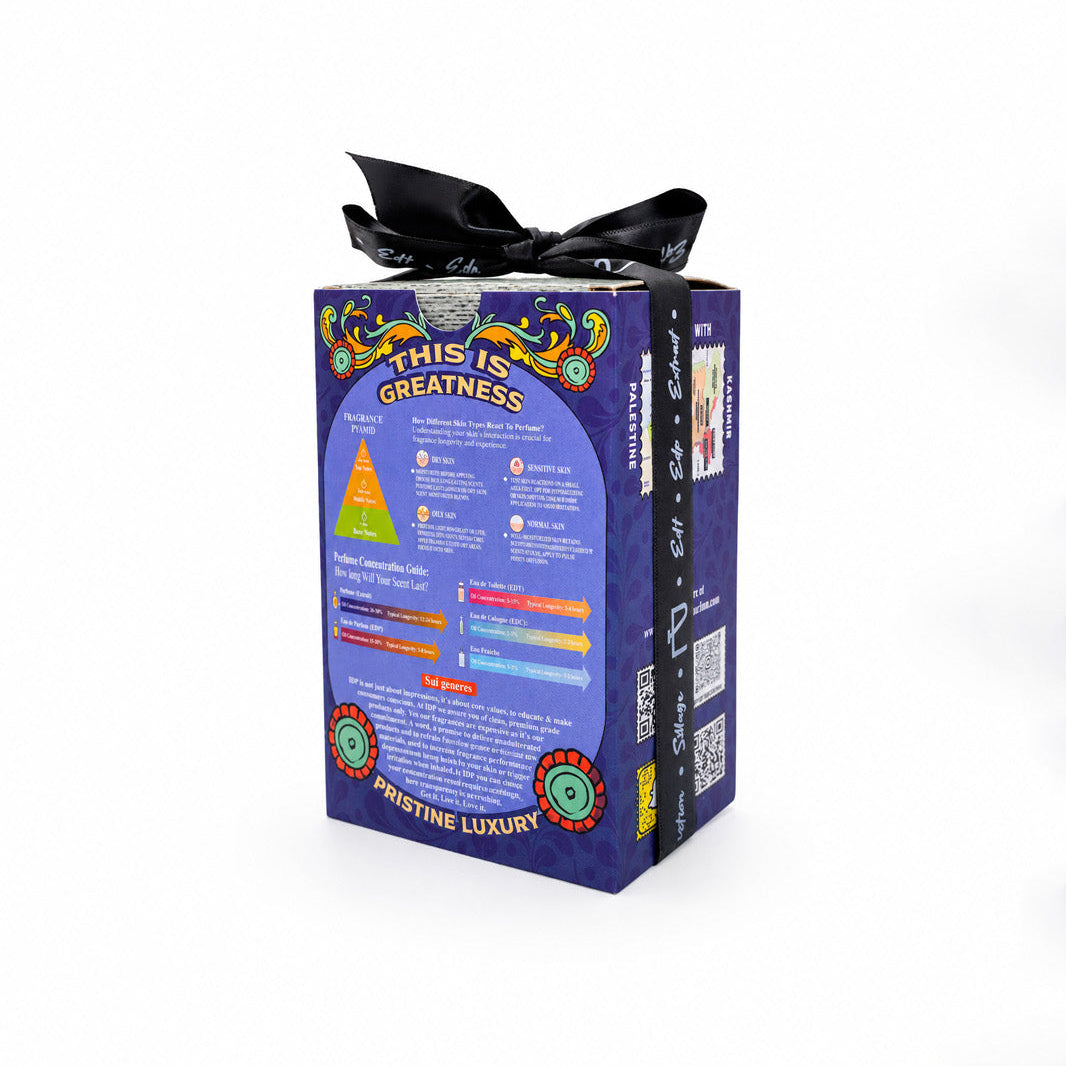 A purple rectangular product box with a black ribbon tied in a bow on top, photographed against a plain white background. The front of the box features colorful printed graphics and text, including a pyramid diagram and the words 'Greatness' and 'Empowering Luxury'.