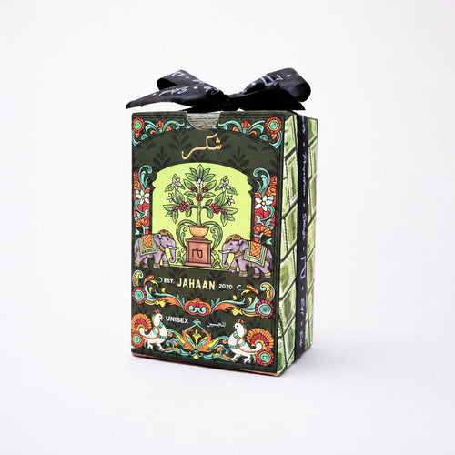 A boxed product wrapped in dark green paper with colorful illustrated elephants, a tree motif, and a black ribbon bow on top, photographed against a plain white background.